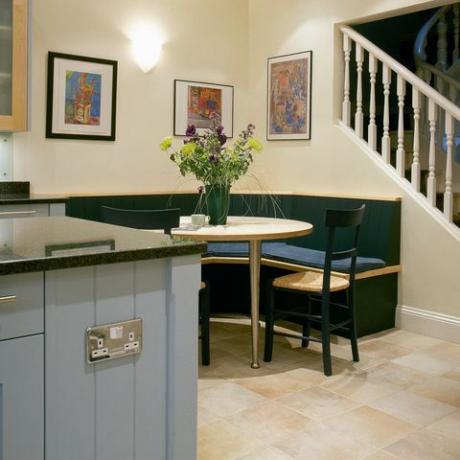 Banqueta de esquina para sentarse a la mesa en la cocina moderna con unidad azul pálido y escalera al piso superior