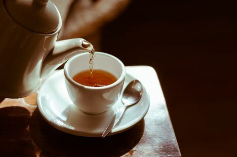 Taza de té en platillo, con té que se vierte,