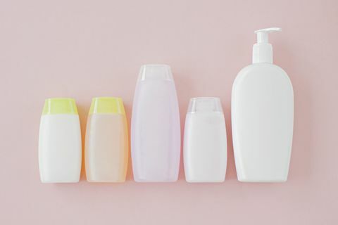 Botellas de cosméticos sin etiquetar sobre un fondo rosa