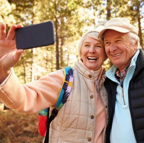 Una pareja mayor en una caminata en un bosque tomando un selfie