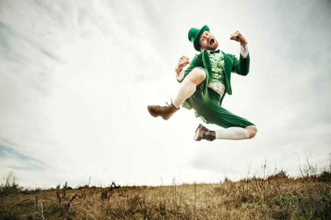 un personaje irlandés estereotipado todo listo para el día de san patricio salta y baila en un campo abierto del espacio de copia del lado del campo irlandés en el cielo y la hierba