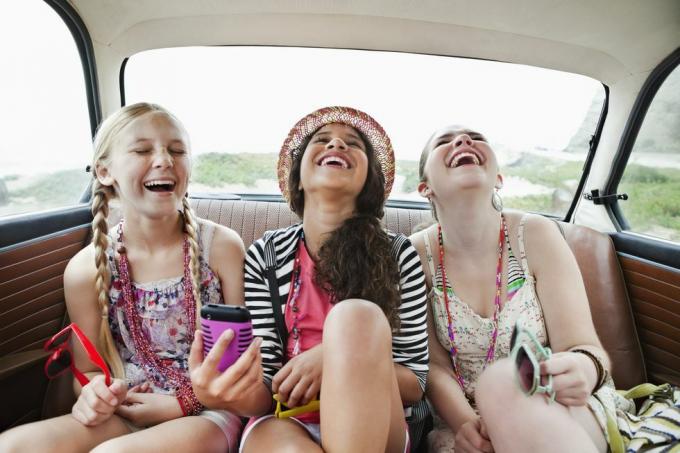 tres niñas riendo en el asiento trasero de un vehículo