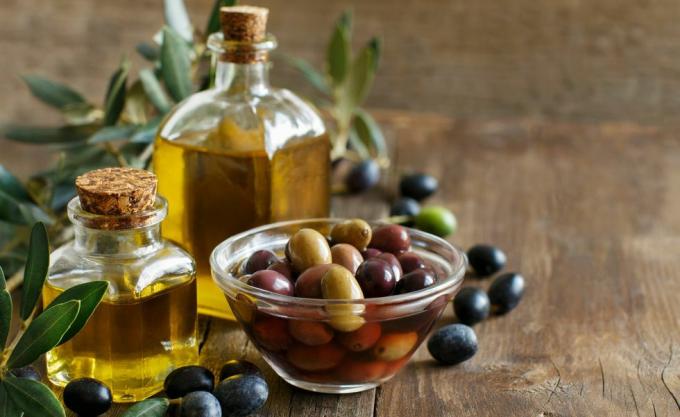 Aceite de oliva y aceitunas sobre fondo de madera
