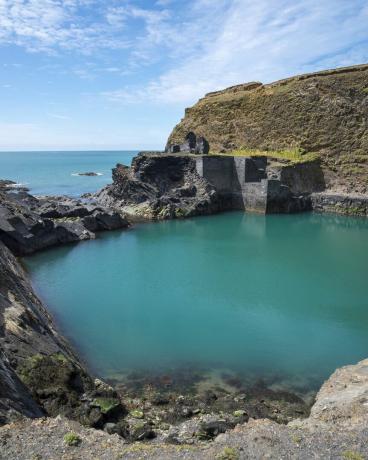 Característica muy conocida en el parque nacional de la costa de Pembrokeshire, una antigua cantera inundada por el mar para crear una piscina de color azul profundo, restos de edificios antiguos junto al agua.