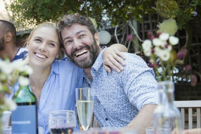 pareja riendo almorzando con amigos en el patio del jardín