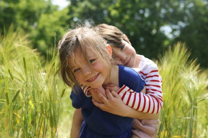 una niña cargando a su hermanito en un campo de trigo