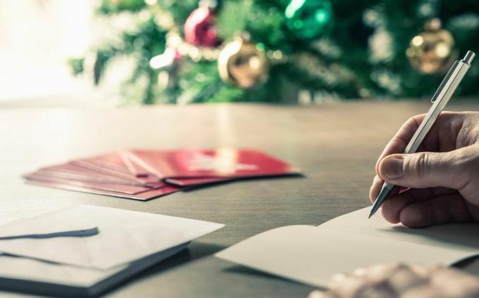 escribir mensajes de tarjetas navideñas frente a un árbol navideño