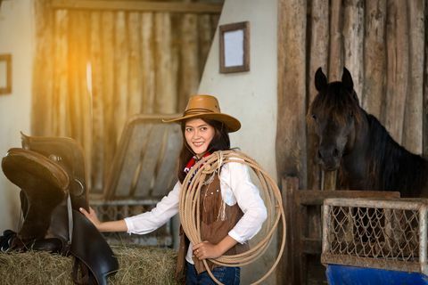 Mujeres vestidas con traje de vaquero con caballo en segundo plano.