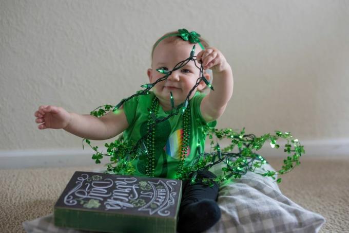 niña vestida de verde jugando con las decoraciones del día de San Patricio, podrías titular a la pequeña señorita trébol en Instagram