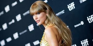 Taylor Swift mirando por encima del hombro en la alfombra roja con un vestido dorado