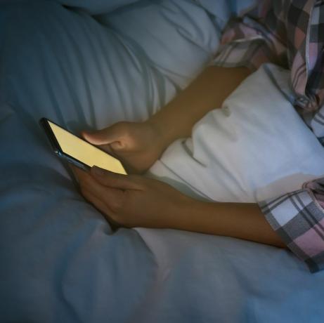 mujer que usa un teléfono inteligente en la cama por la noche, nomofobia de primer plano y problema de trastorno del sueño