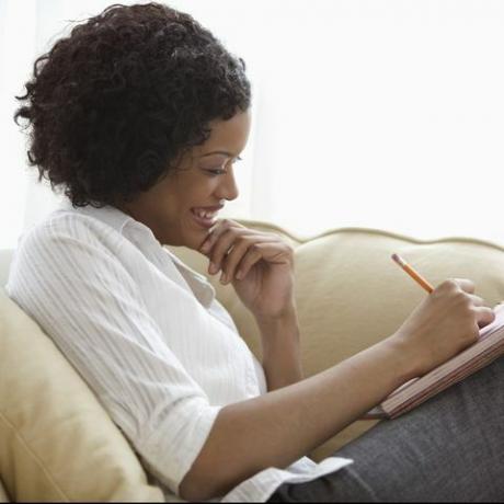 Mujer sentada en el sofá con el bloc de notas en su regazo