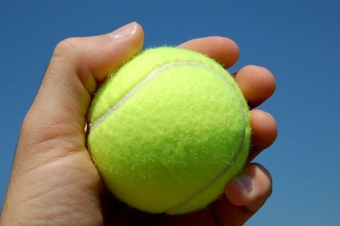 Pelota de tenis en la mano de cerca