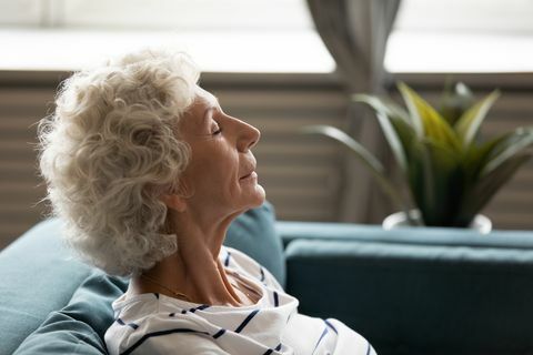 vista lateral cara de cerca de una mujer madura y tranquila de los años 60 ojos cerrados disfrutar del aire fresco pasar tiempo en casa apoyado en el sofá, descansar ganando fuerza mental y física meditación consciente para el concepto de personas mayores