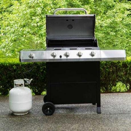 gran cocina de barbacoa al aire libre con tapa en posición abierta en el patio de hormigón de la casa