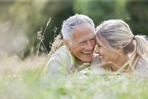 Feliz pareja de ancianos sentados en la hierba larga