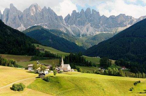 Paisaje de verano del idílico Val di Funes con picos escarpados de la cordillera de Odle (Geisler) en el fondo y una iglesia en el pueblo de Santa Maddalena en el verde valle de hierba en Dolomiti, Tirol del Sur, Italia