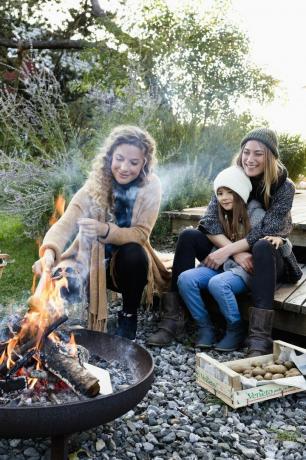 dos mujeres y una niña sentadas junto al fuego, relajándose