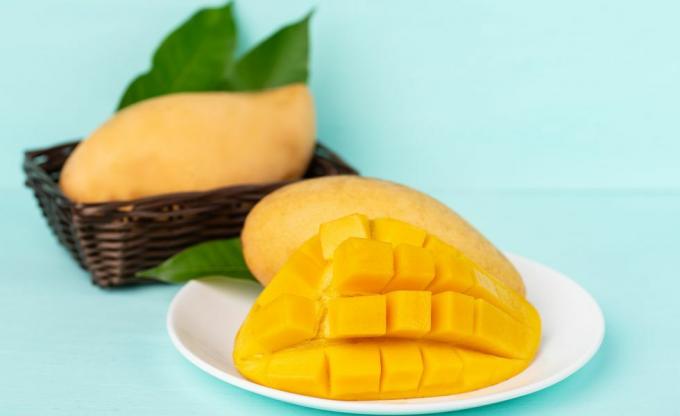 Primer plano de la fruta del mango en la placa sobre fondo azul.
