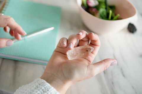 mano de mujer sosteniendo cristales curativos con portátil en segundo plano.