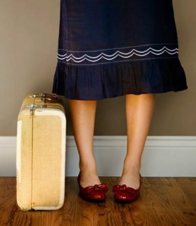 mujer en falda azul y zapatos de rubí con una maleta