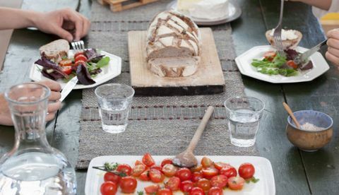 Cerca de pareja almorzando en la mesa con tomates y pan