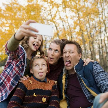 Familia tonta tomando selfie haciendo caras en el parque de otoño