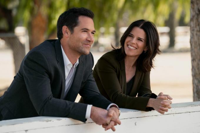los dos personajes, que son ex marido y mujer en la serie, se inclinan sobre una pared al aire libre, sonríen, hablan